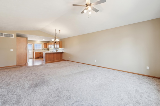 unfurnished living room featuring visible vents, light carpet, ceiling fan with notable chandelier, baseboards, and vaulted ceiling