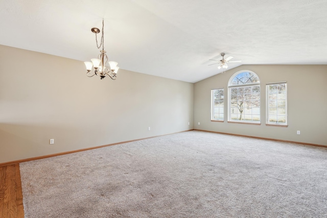 carpeted empty room featuring lofted ceiling, ceiling fan with notable chandelier, and baseboards