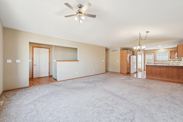 unfurnished living room featuring visible vents, light colored carpet, ceiling fan with notable chandelier, and lofted ceiling