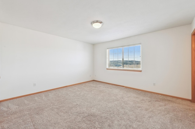 carpeted empty room featuring baseboards