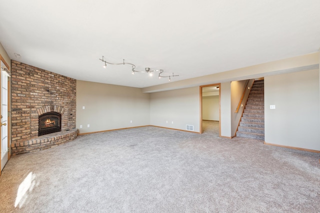 unfurnished living room with visible vents, a brick fireplace, stairway, and carpet floors