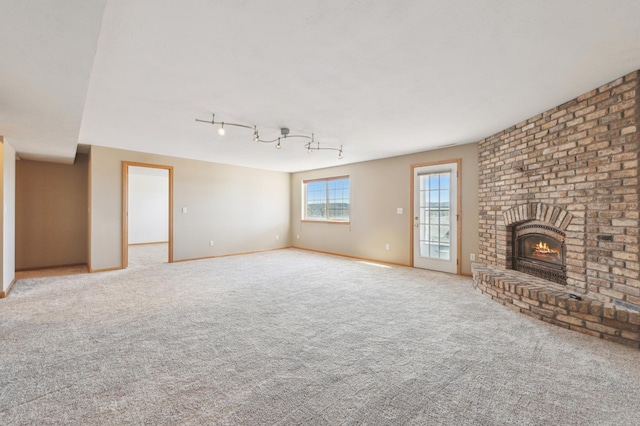 unfurnished living room with baseboards, a brick fireplace, and carpet flooring