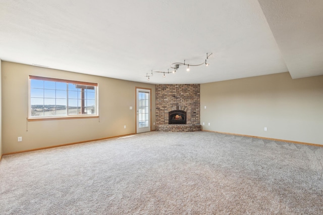 unfurnished living room featuring carpet, a fireplace, baseboards, and a textured ceiling