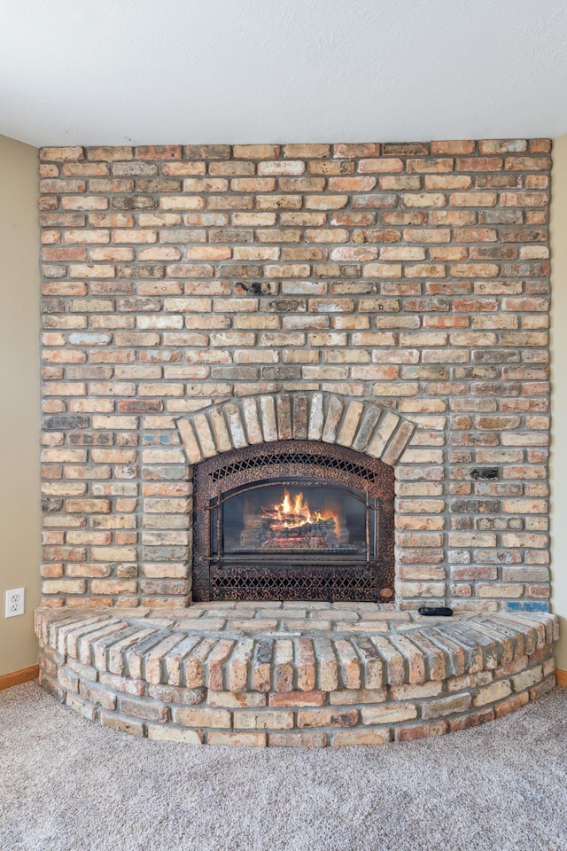 details with a brick fireplace, carpet, and baseboards