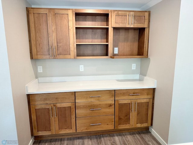 kitchen featuring brown cabinetry, light countertops, baseboards, and wood finished floors