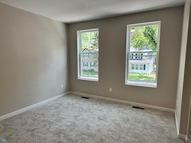 carpeted spare room with visible vents and baseboards