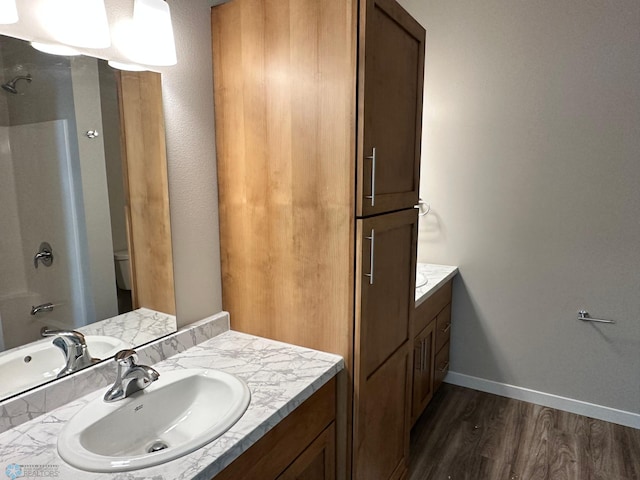 full bath featuring toilet, vanity, baseboards, and wood finished floors