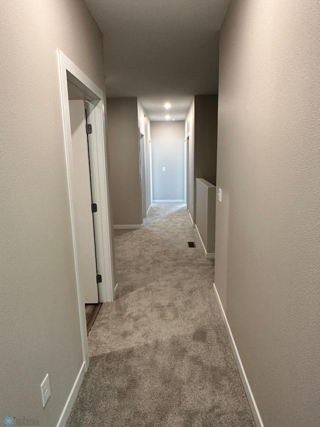 hallway with baseboards, visible vents, and carpet floors