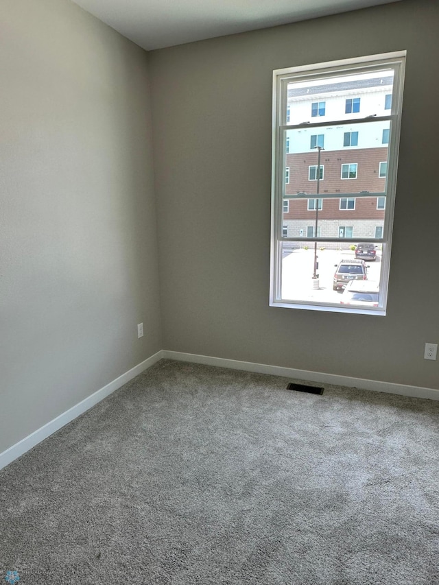 unfurnished room with carpet flooring, baseboards, and visible vents