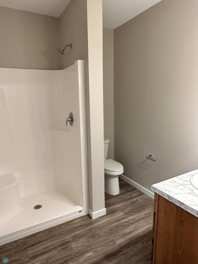 full bathroom featuring baseboards, toilet, a stall shower, wood finished floors, and vanity