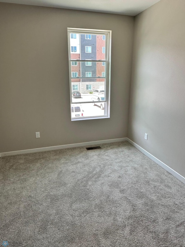 empty room featuring visible vents, baseboards, and carpet