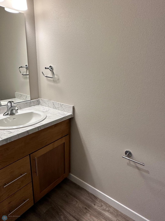 bathroom with baseboards, wood finished floors, and vanity