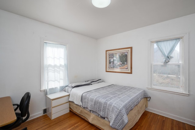 bedroom with visible vents, light wood-type flooring, and baseboards