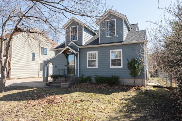 view of front of home with a shingled roof and a front lawn