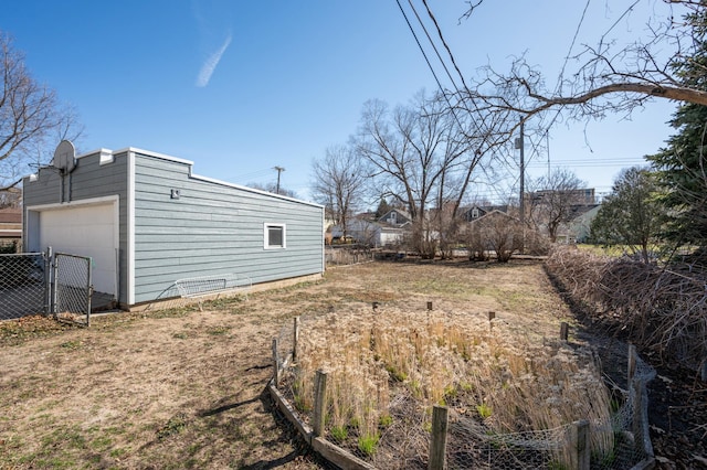 view of yard with a detached garage, an outbuilding, and fence