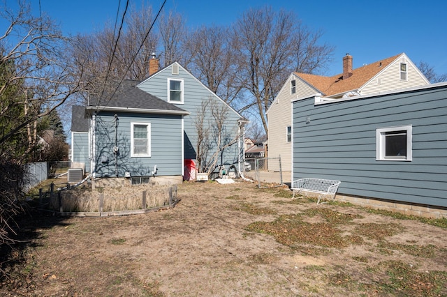 back of house with a shingled roof, central air condition unit, fence, and a chimney