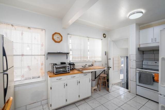 kitchen featuring under cabinet range hood, electric range, plenty of natural light, and freestanding refrigerator