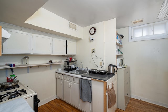 kitchen featuring wood finished floors, visible vents, gas range gas stove, a sink, and light countertops