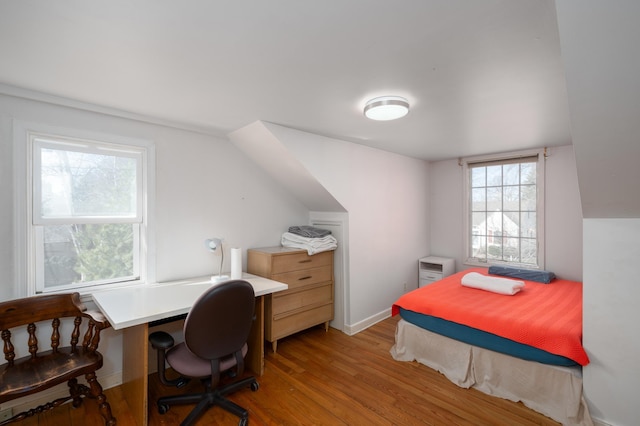 bedroom with vaulted ceiling, wood finished floors, and baseboards