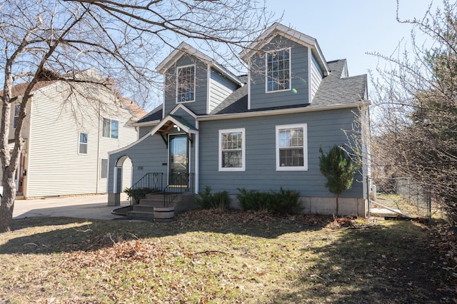 view of front of house featuring a front lawn and roof with shingles