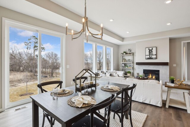 9184 62nd St S, Cottage Grove, MN 55016 - dining space featuring a glass covered fireplace, wood finished floors, a chandelier, and recessed lighting