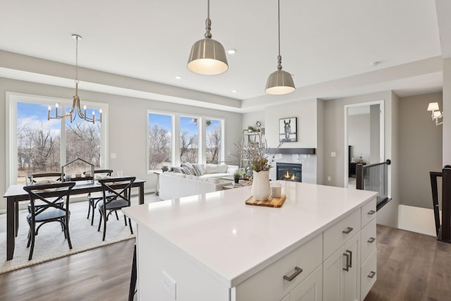 9184 62nd St S, Cottage Grove, MN 55016 - kitchen featuring dark wood-style floors, a glass covered fireplace, a chandelier, white cabinets, and a center island