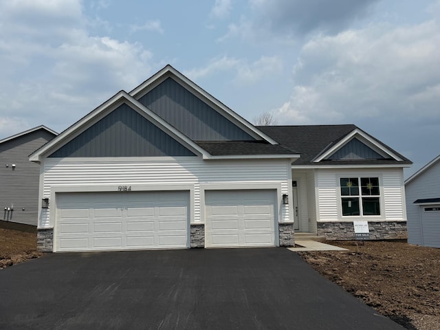 9184 62nd St S, Cottage Grove, MN 55016 - view of front of home with asphalt driveway, stone siding, an attached garage, and roof with shingles