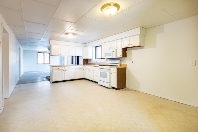 kitchen with white appliances, white cabinets, light floors, and baseboards