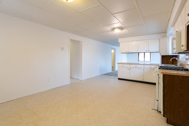 kitchen with range with gas cooktop, light floors, a peninsula, and white cabinetry