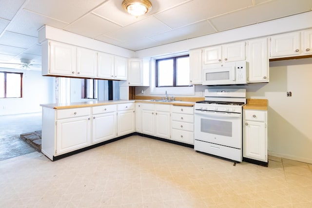 kitchen with a sink, white appliances, and white cabinets