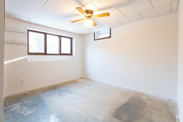 unfurnished room featuring a drop ceiling, ceiling fan, concrete flooring, and baseboards