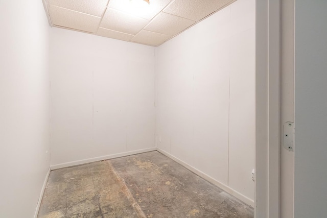 spare room featuring unfinished concrete flooring, baseboards, and a drop ceiling