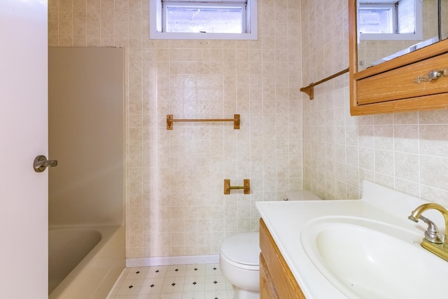 bathroom with tile patterned floors, toilet, tile walls, and vanity