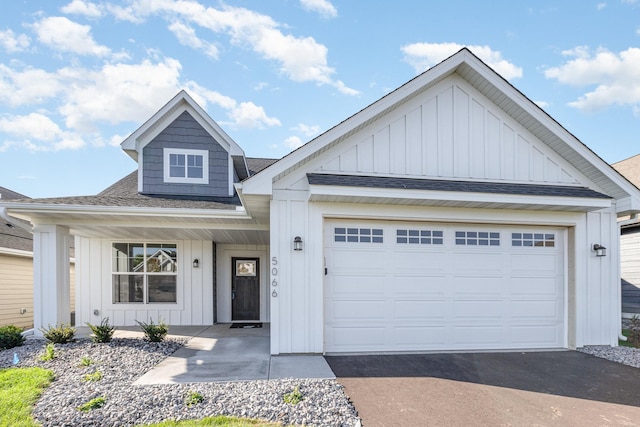 view of front of property featuring aphalt driveway, a garage, board and batten siding, and roof with shingles