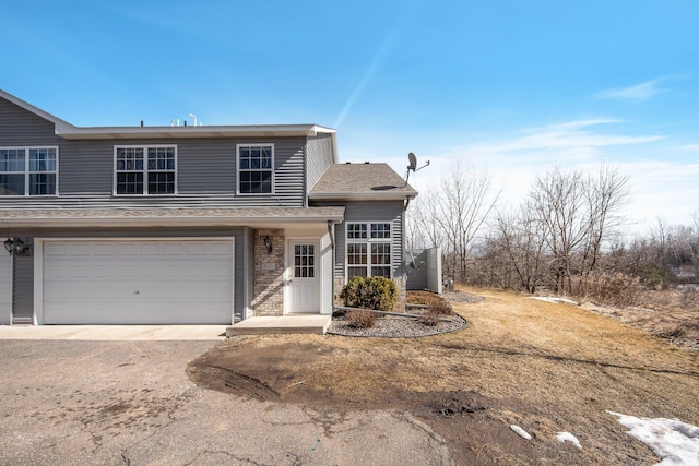 traditional-style house with brick siding, an attached garage, driveway, and a shingled roof