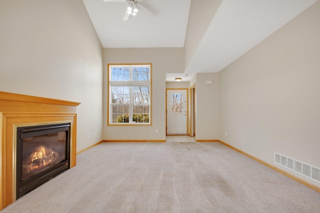 unfurnished living room with visible vents, high vaulted ceiling, a glass covered fireplace, carpet flooring, and baseboards