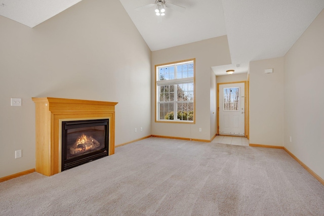 unfurnished living room featuring a glass covered fireplace, baseboards, carpet floors, and high vaulted ceiling