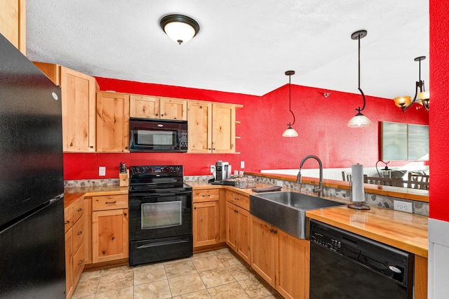 kitchen featuring a sink, pendant lighting, a peninsula, wooden counters, and black appliances