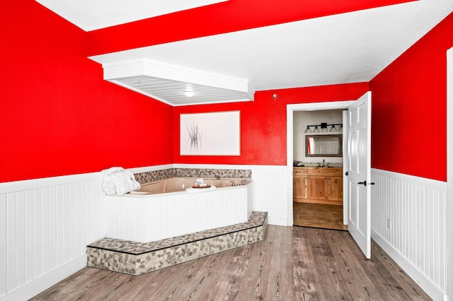 full bath with a wainscoted wall, wood finished floors, vanity, and a garden tub