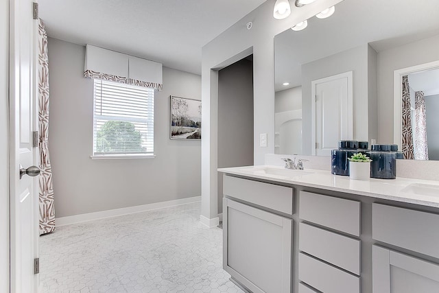 bathroom featuring double vanity, baseboards, and a sink