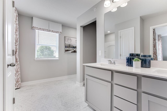 bathroom with double vanity, baseboards, and a sink