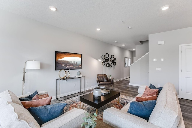 living area with a textured ceiling, recessed lighting, baseboards, wood finished floors, and stairway