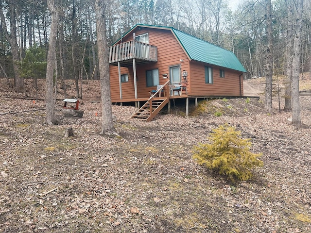 chalet / cabin with a gambrel roof, metal roof, and a balcony