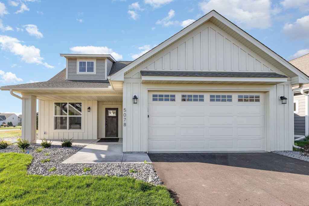 view of front facade featuring aphalt driveway, a garage, board and batten siding, and a shingled roof