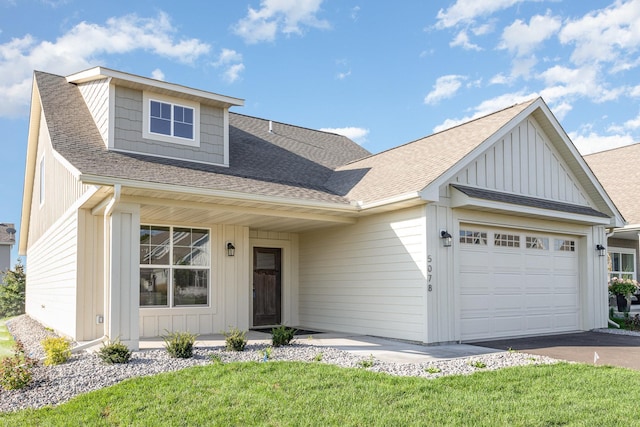 view of front of home with board and batten siding, aphalt driveway, a front yard, roof with shingles, and a garage