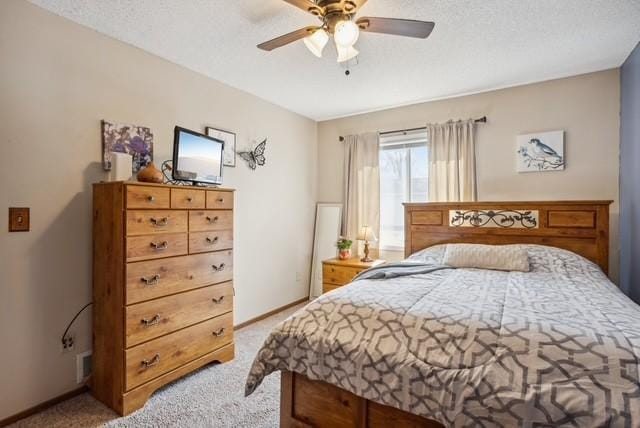 bedroom featuring light carpet, a textured ceiling, baseboards, and a ceiling fan