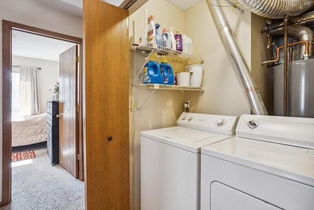 clothes washing area with laundry area, water heater, carpet floors, and washer and clothes dryer