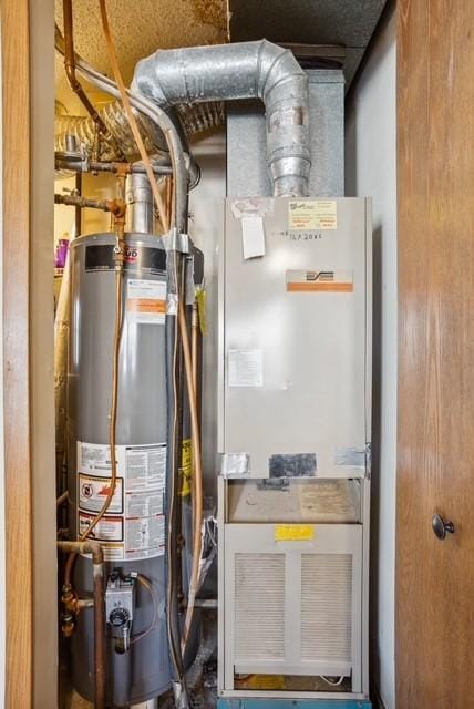 utility room featuring gas water heater and heating unit