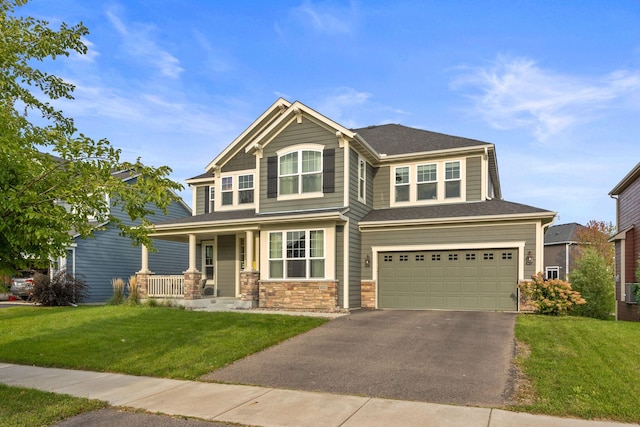 craftsman-style home with an attached garage, a front lawn, covered porch, stone siding, and driveway