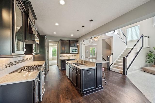 kitchen featuring dark wood-type flooring, a kitchen breakfast bar, appliances with stainless steel finishes, and a sink